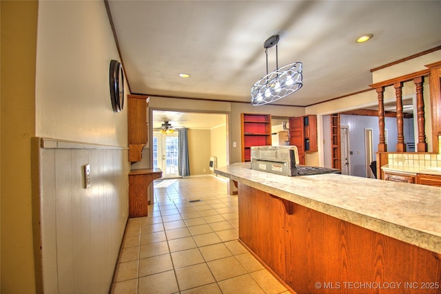 6508 W Cameron St, Sand Springs, OK 74127 - kitchen featuring light tile patterned floors, a ceiling fan, light countertops, wainscoting, and a kitchen breakfast bar