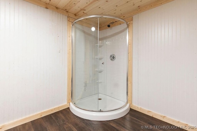 bathroom with a stall shower, baseboards, and wood finished floors