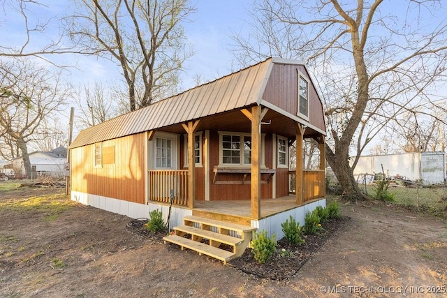 view of front facade with covered porch, metal roof, a gambrel roof, and fence