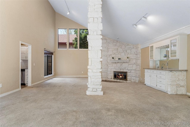 6505 S Oswego Ave, Tulsa, OK 74136 - unfurnished living room with a stone fireplace, track lighting, indoor wet bar, and carpet floors