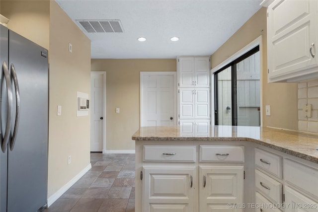 6505 S Oswego Ave, Tulsa, OK 74136 - kitchen featuring freestanding refrigerator, white cabinetry, light stone countertops, baseboards, and visible vents