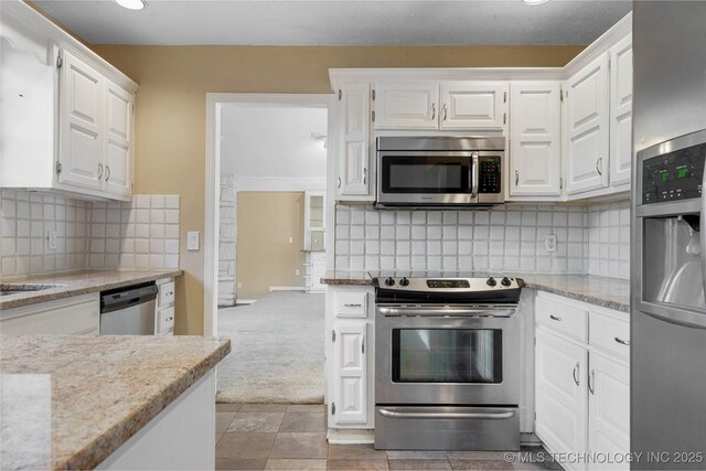 6505 S Oswego Ave, Tulsa, OK 74136 - kitchen with white cabinetry, tasteful backsplash, light stone countertops, light carpet, and appliances with stainless steel finishes