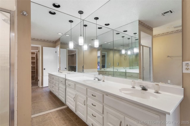 6505 S Oswego Ave, Tulsa, OK 74136 - bathroom featuring a spacious closet, a shower stall, a sink, visible vents, and double vanity