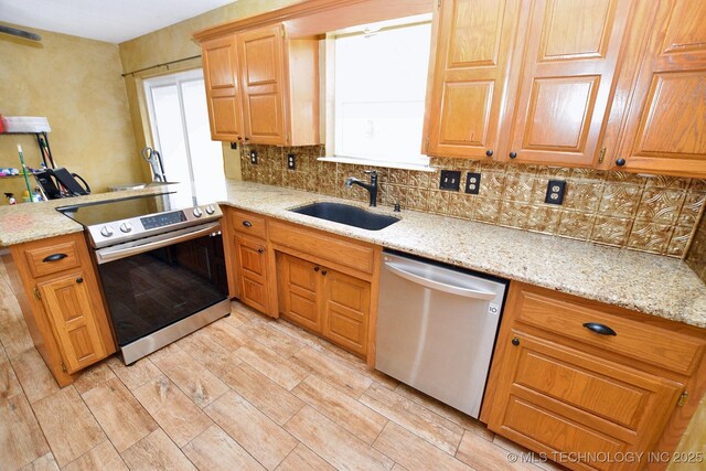 1430 Williams St, Fort Gibson, OK 74434 - kitchen with backsplash, light stone countertops, appliances with stainless steel finishes, a peninsula, and a sink