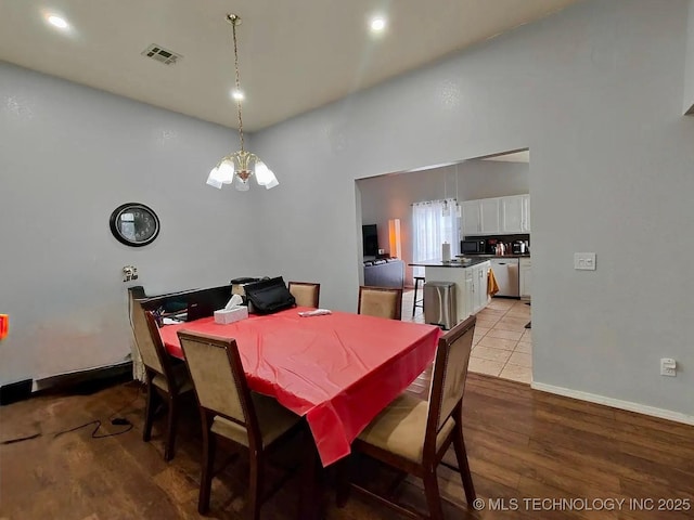 dining room with visible vents, a notable chandelier, wood finished floors, baseboards, and a towering ceiling