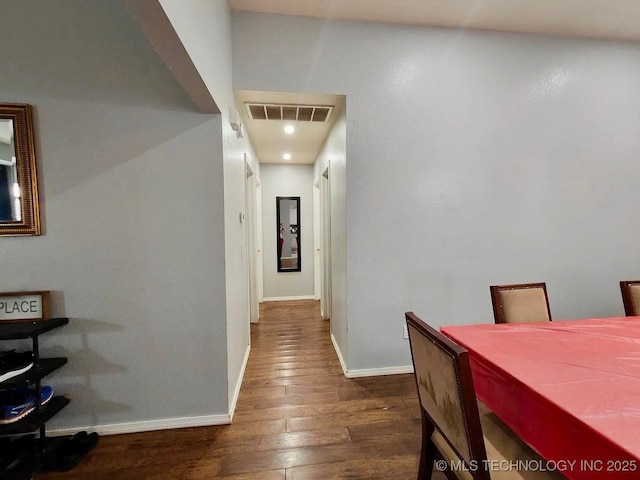 hallway with dark wood-style floors, visible vents, and baseboards