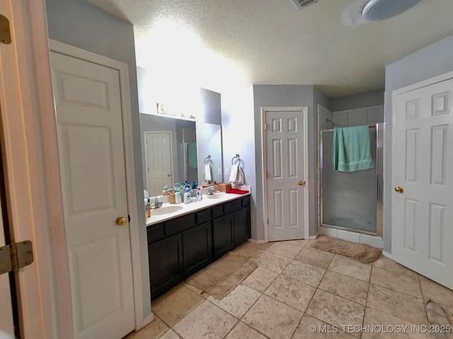 bathroom with a shower stall, double vanity, and a sink