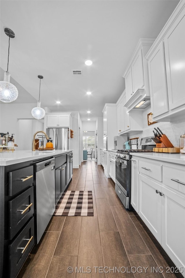 kitchen with light countertops, dark wood finished floors, appliances with stainless steel finishes, and white cabinetry