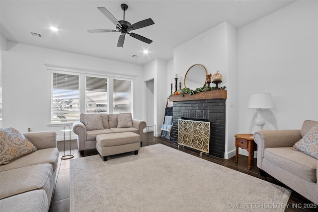 living room with visible vents, baseboards, a fireplace, dark wood-type flooring, and a ceiling fan