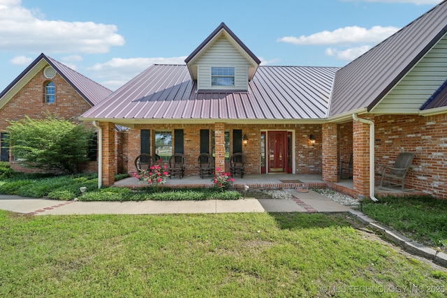 11712 E 121st St, Collinsville, OK 74021 - view of front facade featuring brick siding, a front lawn, metal roof, and a porch
