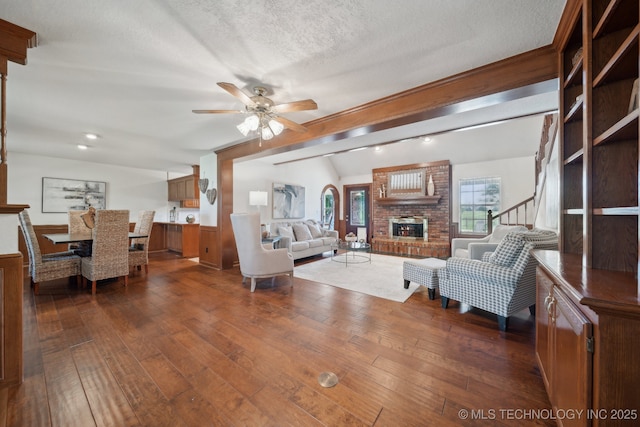 11712 E 121st St, Collinsville, OK 74021 - living room featuring a fireplace, lofted ceiling, dark wood finished floors, ceiling fan, and a textured ceiling