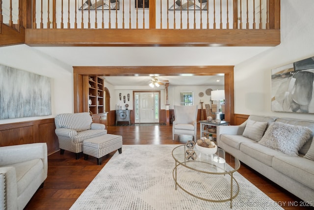 11712 E 121st St, Collinsville, OK 74021 - living room featuring a towering ceiling, dark wood finished floors, wainscoting, a ceiling fan, and wood walls
