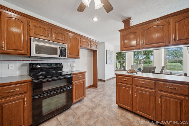 11712 E 121st St, Collinsville, OK 74021 - kitchen featuring white microwave, range with two ovens, brown cabinetry, ceiling fan, and light countertops