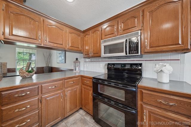 11712 E 121st St, Collinsville, OK 74021 - kitchen featuring double oven range, stainless steel microwave, brown cabinetry, tasteful backsplash, and a textured ceiling