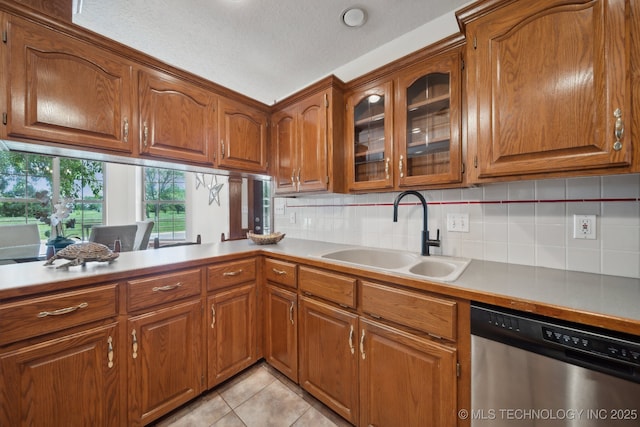11712 E 121st St, Collinsville, OK 74021 - kitchen with stainless steel dishwasher, a sink, brown cabinetry, glass insert cabinets, and a textured ceiling