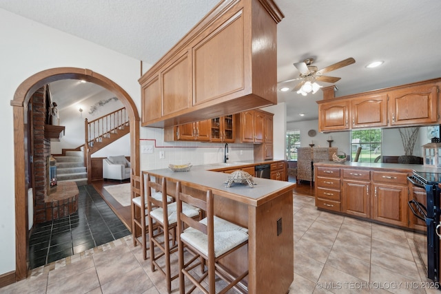 11712 E 121st St, Collinsville, OK 74021 - kitchen featuring double oven range, ceiling fan, a peninsula, arched walkways, and a breakfast bar