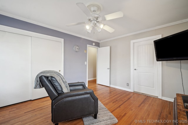 living area with a ceiling fan, wood finished floors, baseboards, and ornamental molding