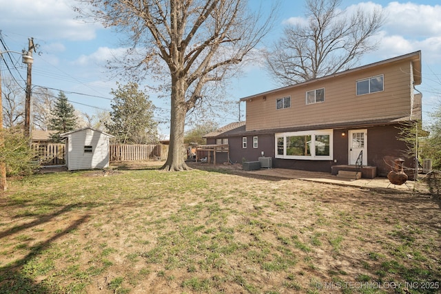 rear view of house featuring an outbuilding, cooling unit, fence, a shed, and a lawn