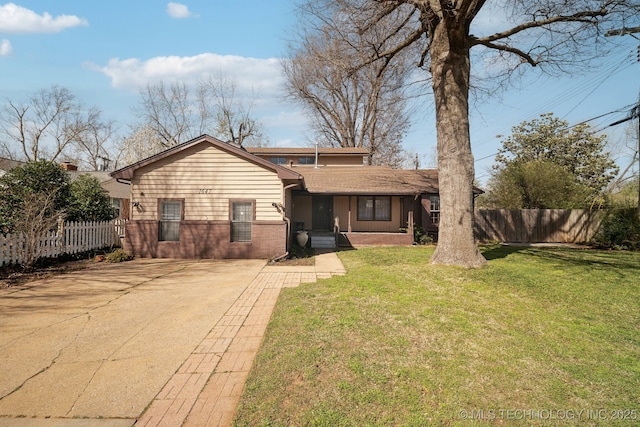 view of front of home with brick siding, concrete driveway, a front lawn, and fence
