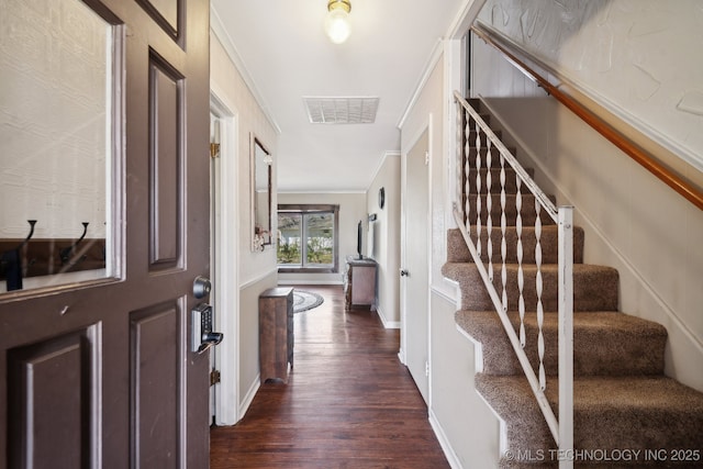 foyer entrance with visible vents, dark wood-type flooring, ornamental molding, and stairway