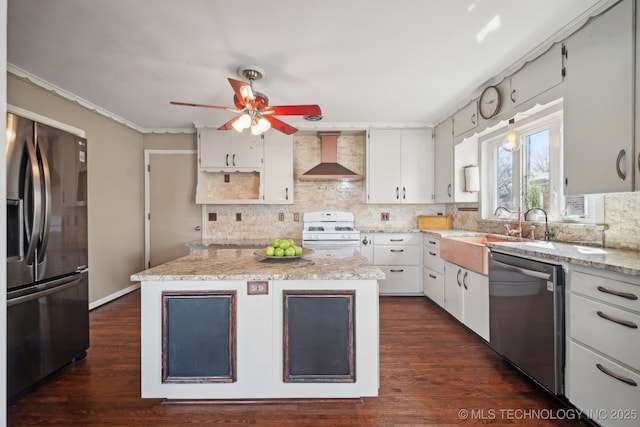 kitchen featuring a sink, appliances with stainless steel finishes, wall chimney exhaust hood, white cabinets, and decorative backsplash