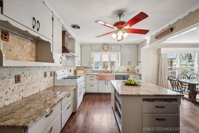 kitchen featuring visible vents, backsplash, wall chimney range hood, white gas stove, and a ceiling fan