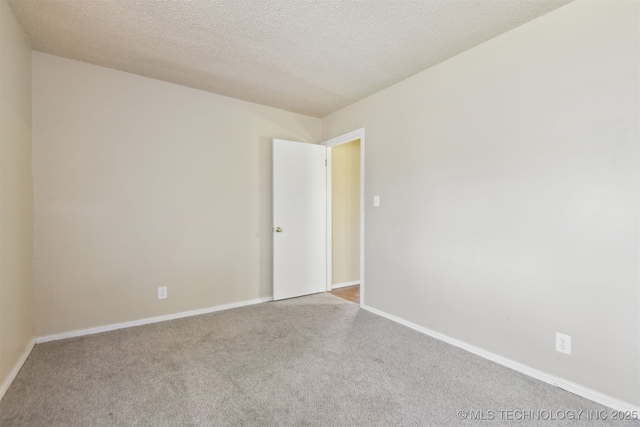 carpeted empty room featuring baseboards and a textured ceiling