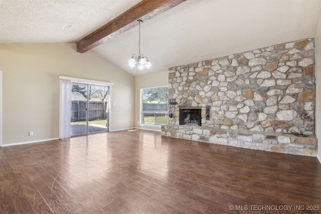 unfurnished living room featuring lofted ceiling with beams, a textured ceiling, wood finished floors, a stone fireplace, and a chandelier