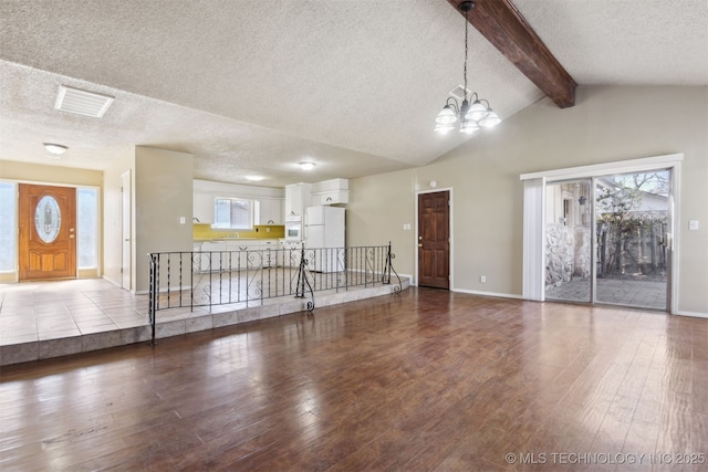 unfurnished living room featuring visible vents, a textured ceiling, an inviting chandelier, and wood finished floors