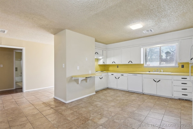 kitchen with visible vents, a sink, white cabinets, light countertops, and dishwasher
