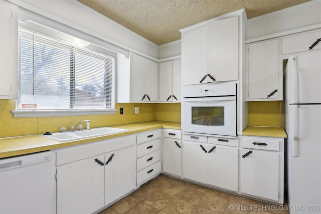 kitchen with a sink, white appliances, a textured ceiling, and light countertops