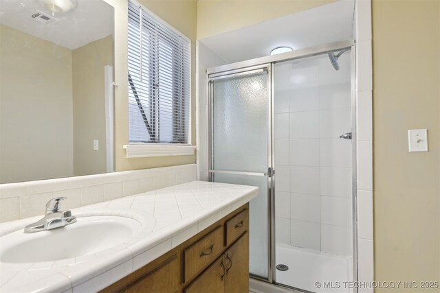 bathroom with visible vents, a stall shower, and vanity