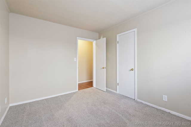 carpeted spare room featuring crown molding and baseboards