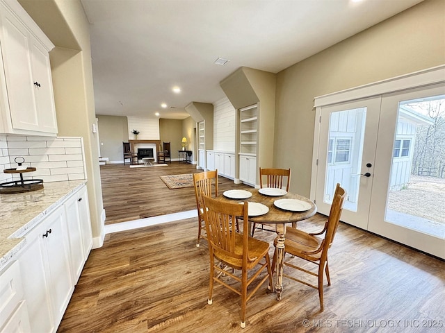 17022 S 579th Rd, Tahlequah, OK 74464 - dining space with wood finished floors, a fireplace, recessed lighting, built in shelves, and french doors