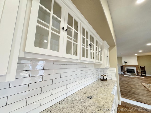 17022 S 579th Rd, Tahlequah, OK 74464 - kitchen with backsplash, white cabinets, open floor plan, light stone countertops, and glass insert cabinets