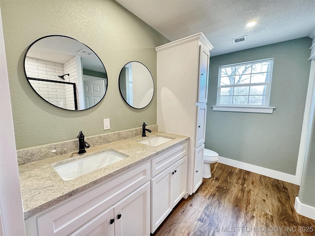 17022 S 579th Rd, Tahlequah, OK 74464 - full bathroom with double vanity, wood finished floors, tiled shower, and a textured ceiling