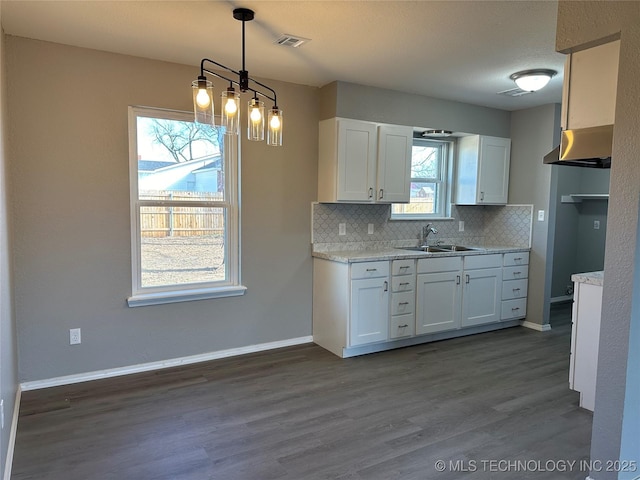 kitchen featuring tasteful backsplash, visible vents, baseboards, white cabinets, and a sink