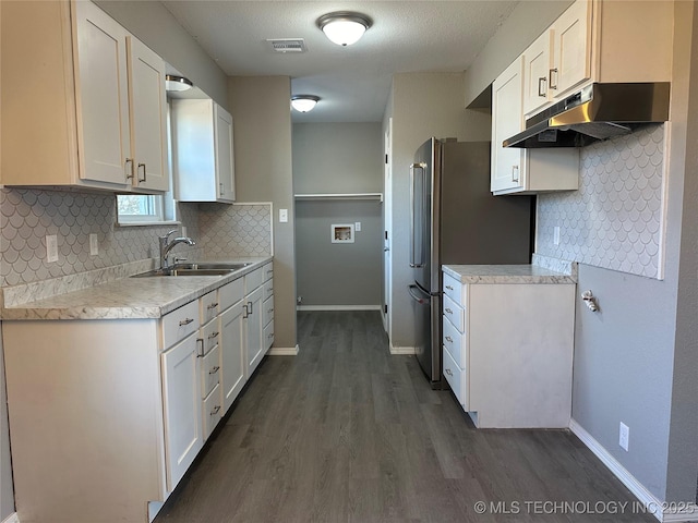 kitchen featuring visible vents, a sink, under cabinet range hood, light countertops, and dark wood-style flooring