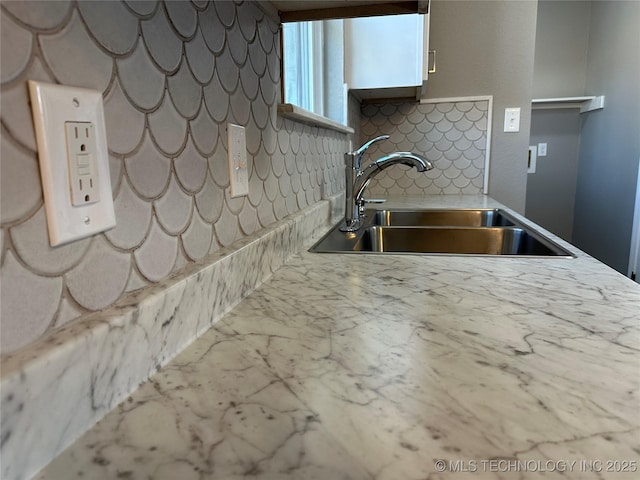 kitchen featuring white cabinetry, light countertops, tasteful backsplash, and a sink