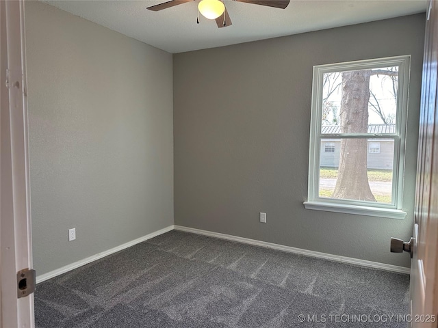 empty room with baseboards, dark carpet, and a ceiling fan
