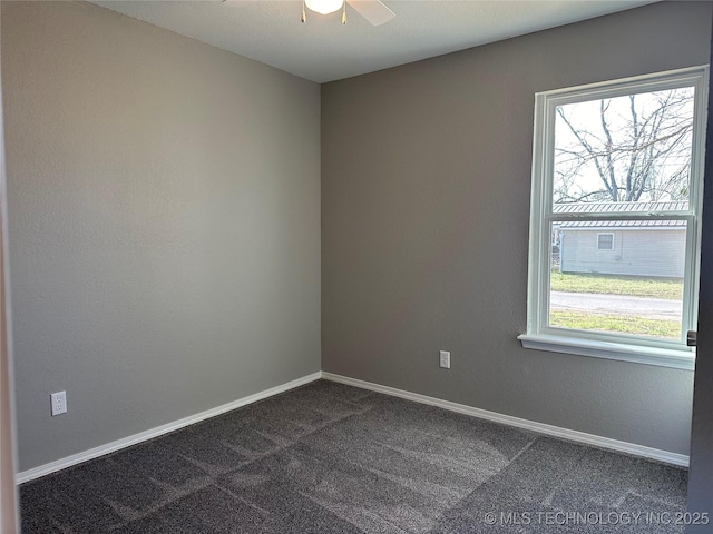 empty room with baseboards, dark carpet, and ceiling fan