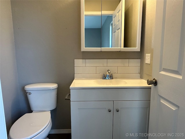 half bath with tasteful backsplash, toilet, and vanity