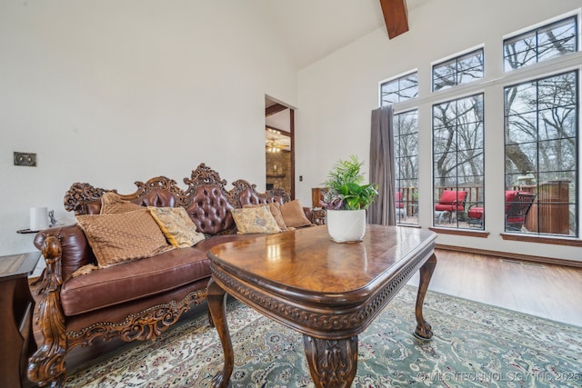 living area featuring beamed ceiling, wood finished floors, and high vaulted ceiling