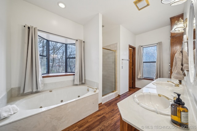 bathroom with a sink, a jetted tub, wood finished floors, and a stall shower
