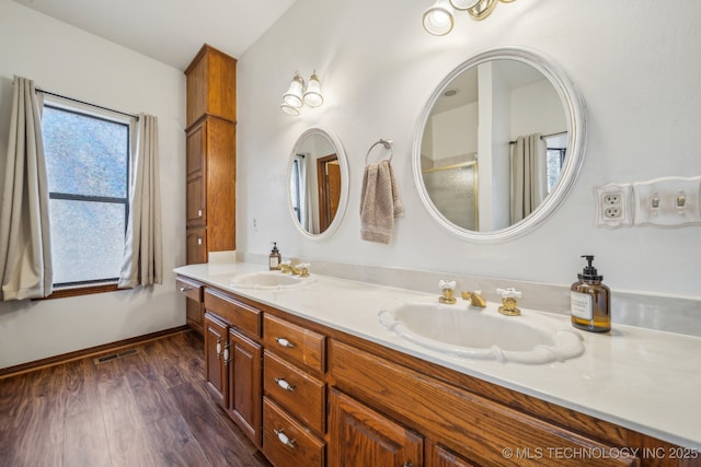 bathroom featuring double vanity, wood finished floors, visible vents, and a sink