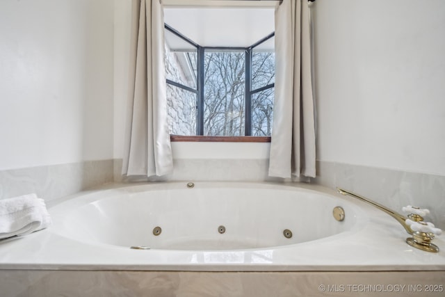 bathroom featuring a wealth of natural light and a tub with jets