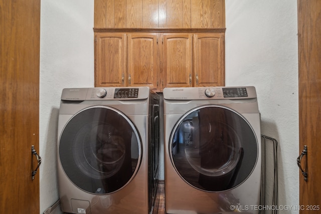 laundry room featuring washer and dryer, cabinet space, and a textured wall