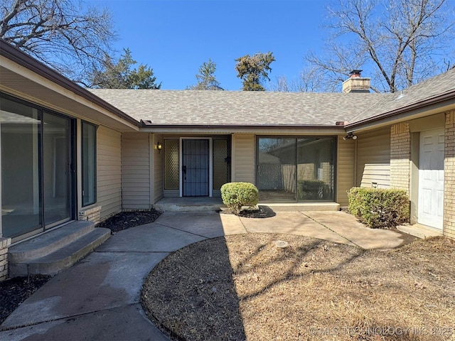 4760 S Irvington Ave, Tulsa, OK 74135 - view of exterior entry with brick siding, a chimney, and roof with shingles