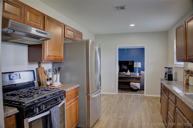 46 S 188th E Ave, Tulsa, OK 74108 - kitchen featuring visible vents, under cabinet range hood, light wood-type flooring, appliances with stainless steel finishes, and brown cabinetry