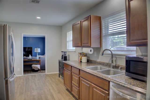 46 S 188th E Ave, Tulsa, OK 74108 - kitchen with light wood finished floors, baseboards, brown cabinets, appliances with stainless steel finishes, and a sink